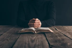 A man does daily prayer to God with his hands on the Bible.